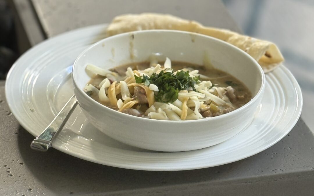 a bowl of pork green chili with cheese on top