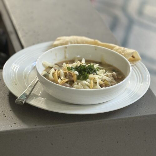 a bowl of pork green chili with cheese on top